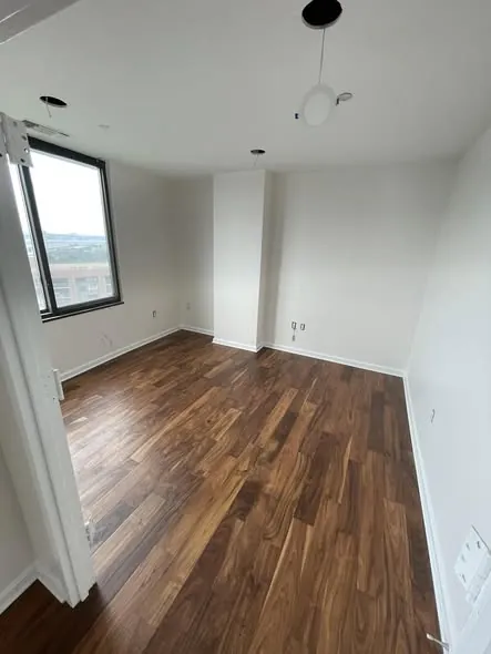 Bedroom with newly installed hardwood flooring and clean baseboard transitions